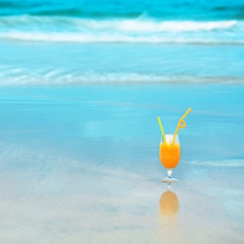 Glass of orange juice on the beach