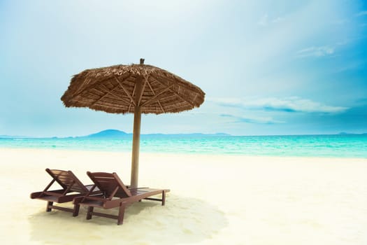 Sandy tropical beach with deck chairs in sunny day