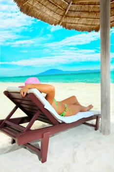 Young woman sunbathing on the chair near the ocean
