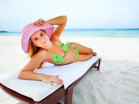 Young woman sunbathing on the chair near the ocean