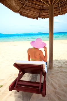 Young woman sunbathing on the chair near the ocean