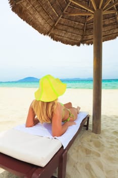 Young woman sunbathing on the chair near the ocean