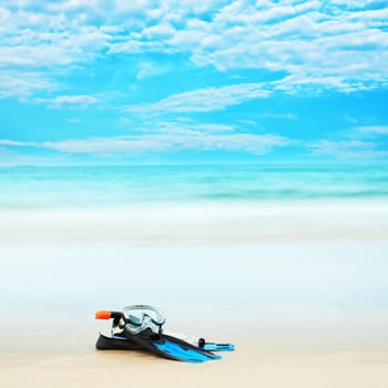Snorkeling equipment mask and fins on white sand beach.