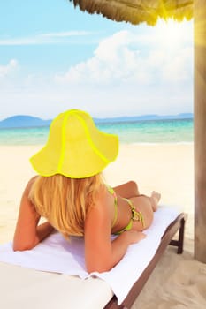 Young woman sunbathing on the chair near the ocean