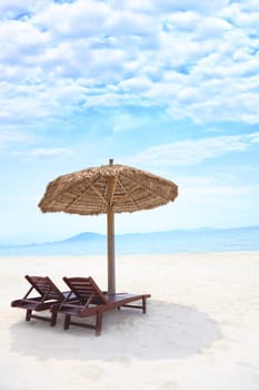 Sandy tropical beach with deck chairs in sunny day