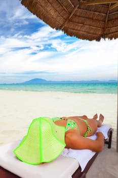 Young woman sunbathing on the chair near the ocean