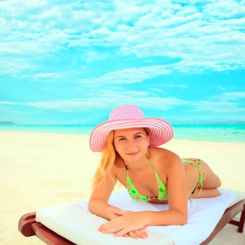 Young woman sunbathing on the chair near the ocean