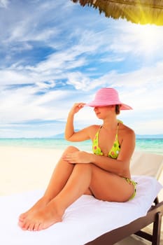 Young woman sunbathing on the chair near the ocean