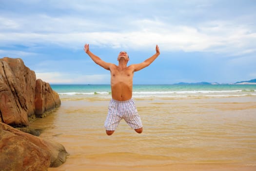 Young man jumping on the tropical beach