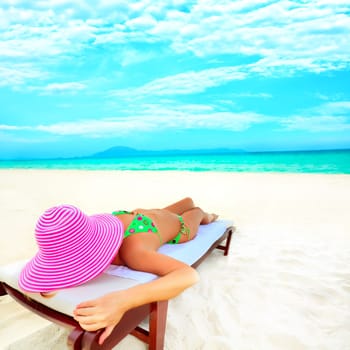 Young woman sunbathing on the chair near the ocean