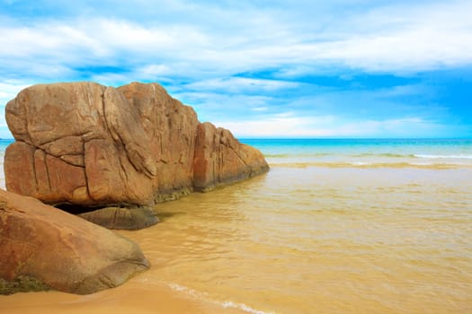 Tropical beach with rock and cloudu sky