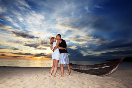 Couple kissing at sunset time on romantic tropical beach