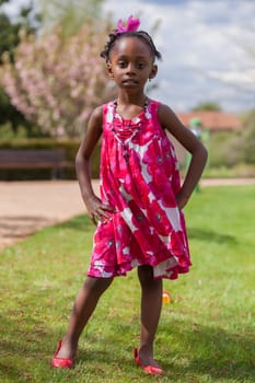 Outdoor portrait of a cute african american little girl, with the hands on the hips
