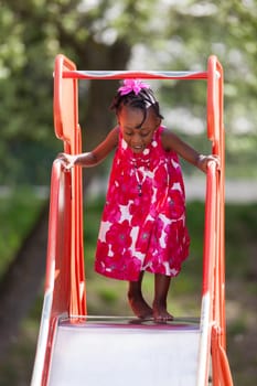 Outdoor Portrait of a cute african american little girl playing at playground