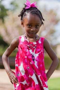 Outdoor portrait of a cute african american little girl, with the hands on the hips