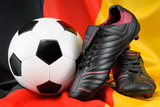 Football and black shoes elegantly arranged in the German national colours