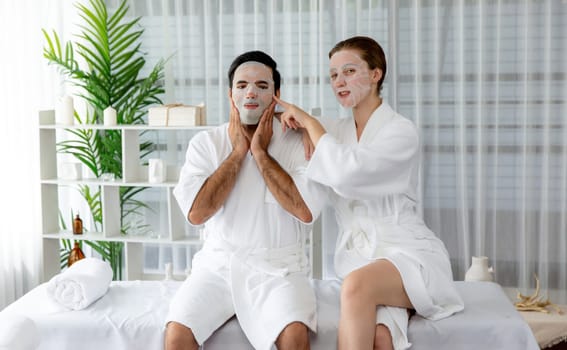 Serene modern daylight ambiance of spa salon, couple customer indulges in rejuvenating with facial skincare mask. Facial skin treatment and beauty cosmetology procedure for face. Quiescent