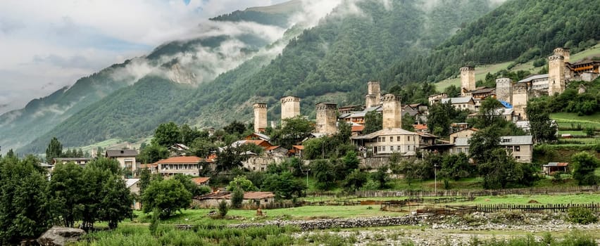 Pamorama of picturesque Mestia village in Svaneti region, Georgia. Green dense forest and mountaons covered with fog