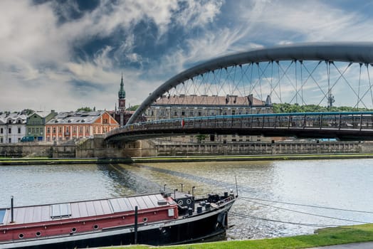 Ancient bridge over the calm river in Krakow, Poland and a small yacht traveling