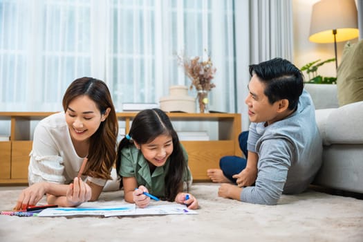Asian family lying on floor painting with little child daughter in living room, Happy Father Mother and daughter drawing together on paper at home, Loving family activity enjoy