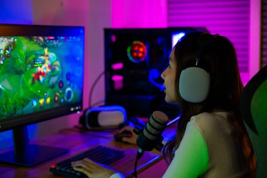 Asian young gamer woman playing video games online on computer she live stream and chat with fans, Happy streamer female talking with microphone in gaming room, game streaming concept