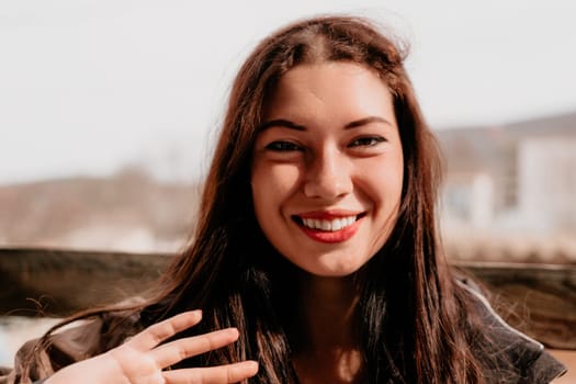 Happy young smiling woman with freckles outdoors portrait. Soft sunny colors. Outdoor close-up portrait of a young brunette woman and looking to the camera, posing against nature background.