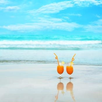 Two glasses of orange juice on tropical beach