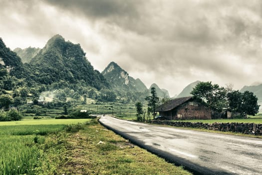 Rural landscape with road  house and mountains.