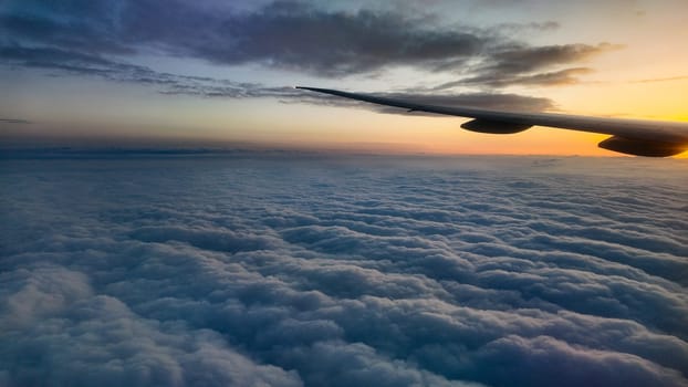 Beautiful clouds illuminated by a sunset seen from above in the sky
