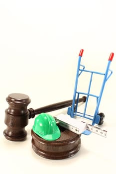 Judge's gavel with construction helmet and folding rule against light background