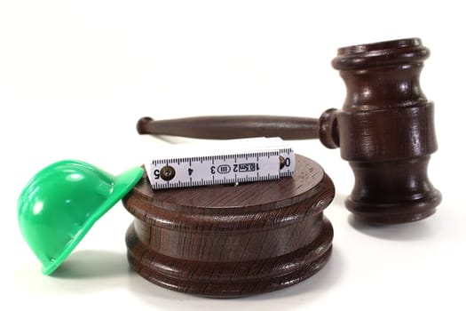 Judge's gavel with construction helmet and folding rule against light background