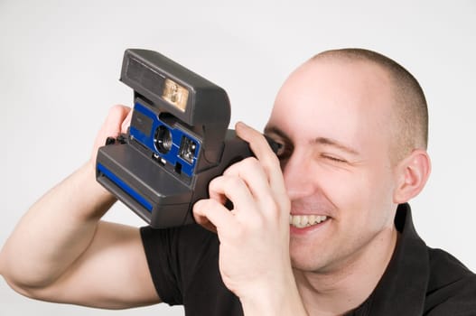 Head and shoulders shot of young man posing with instant camera against white background