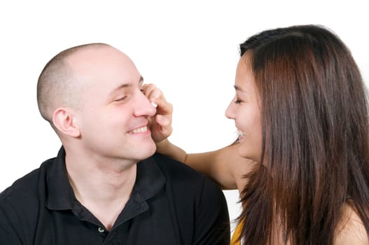 Head and shoulders portrait of a young couple dabbing white cream on each other's noses against a white background