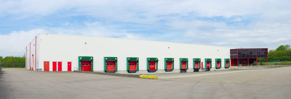 panoramic view of the front of an industrial warehouse with numbered red loading docks