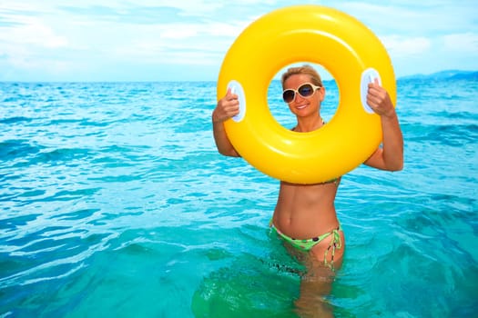Funny woman with yellow tube in the ocean