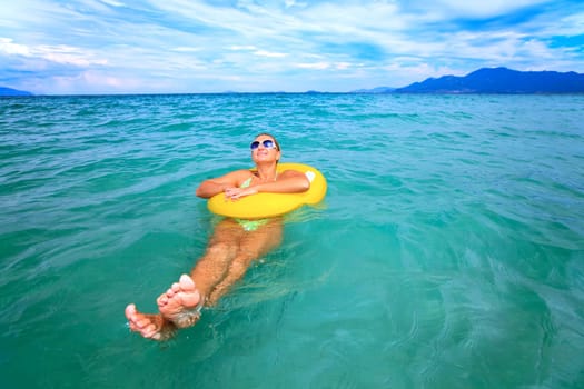 Woman relaxing with yellow tube in tropical lagoon