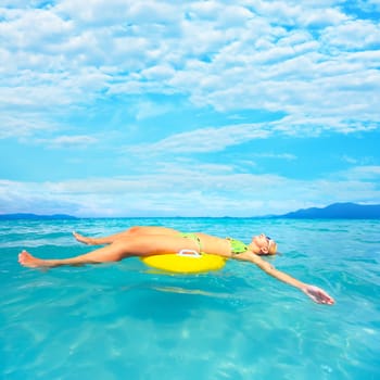 Woman relaxing on inner tube in clean blue ocean