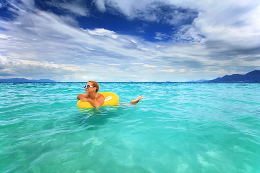 Woman swimming with yellow tube in the sea