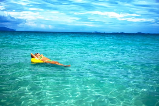 Woman relaxing with yellow tube in the ocean
