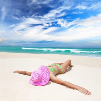Woman in pink hat lies on the beach