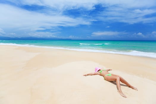 Woman in pink hat lies on the beach