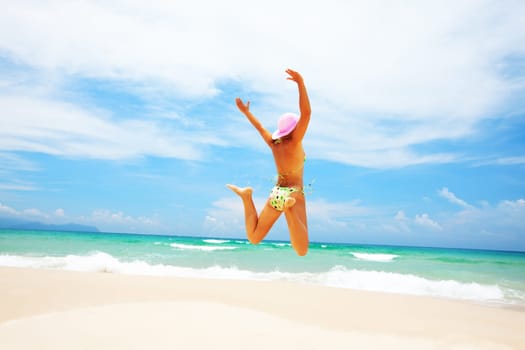 Young woman in bikini  jumping on the tropical beach