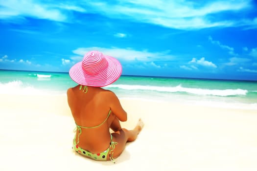 Woman in pink hat sunbathing on the beach