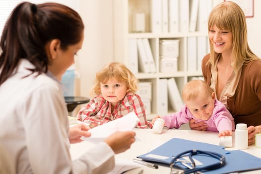 Young woman with two little children girl speak to pediatrician