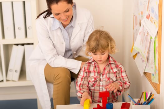 Female pediatrician playing with little girl at medical office
