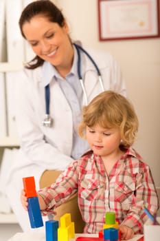 Female pediatrician playing with little girl at medical office