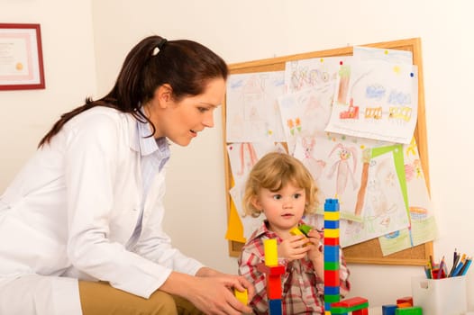 Female pediatrician playing with little girl at medical office