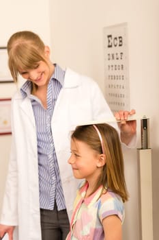 Pediatrician measure height of young girl at medical office