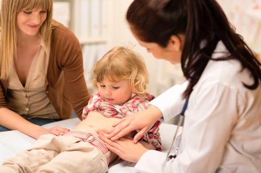 Little girl having tummy examination by pediatrician at medical office