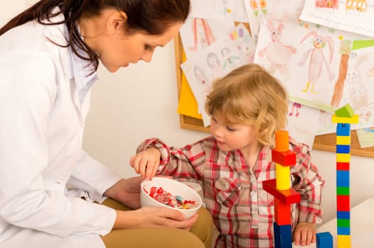 Female pediatrician offering lolly to child reward for bravery